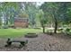 Backyard view featuring barn, garden, fire pit and an outdoor bench under mature trees at 104 Whisper Trce, Peachtree City, GA 30269