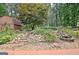 Landscaped backyard with stone steps leading to a charming pond and barn, surrounded by lush greenery at 104 Whisper Trce, Peachtree City, GA 30269