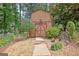 Charming barn with double doors, flanked by greenery, set amongst a gravel path at 104 Whisper Trce, Peachtree City, GA 30269