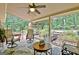 Relaxing covered patio featuring comfortable seating, a ceiling fan, and views of the serene backyard with a small bridge at 104 Whisper Trce, Peachtree City, GA 30269