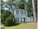 Charming two-story home with light blue siding and black shutters surrounded by mature trees at 4981 Millstone Walk, Stone Mountain, GA 30088
