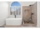 Elegant bathroom featuring a freestanding tub, tile shower, and large arched window at 1007 Fairway Seven, Villa Rica, GA 30180
