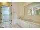 Relaxing bathroom features a bathtub, an open walk-in closet, and white tiled floors and walls at 1880 Hickory Station Cir, Snellville, GA 30078