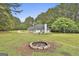 A fire pit and large, well-maintained backyard surrounded by trees and green grass creating a welcoming outdoor space at 391 Massengale Rd, Brooks, GA 30205