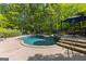 Backyard pool and spa surrounded by lush trees and a patio, perfect for outdoor relaxation and entertainment at 110 Woodland Rd, Fayetteville, GA 30214