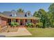 Inviting brick home featuring a covered porch, dormer windows, and lush landscaping at 637 Lakeview Dr, Newborn, GA 30056