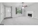 Living room featuring neutral paint, plush carpet, fireplace, a ceiling fan, large window, and front entry at 1152 Sunday Ln, Jonesboro, GA 30238