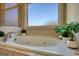Bright bathroom with soaking tub, frosted window, and tiled walls with decorative trim at 4180 Mount Paran Dr, Social Circle, GA 30025