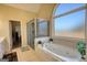 Bright bathroom featuring a soaking tub with jets, tiled shower, and large arched window at 4180 Mount Paran Dr, Social Circle, GA 30025