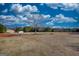 Expansive yard with sparse vegetation, trees in the background, and a storage shed in the distance under a beautiful sky at 4180 Mount Paran Dr, Social Circle, GA 30025