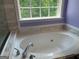 Close-up of a white soaking tub with tiled surround and fixture hardware at 2828 Hicks Sw Rd, Marietta, GA 30060
