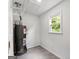 A water heater is installed in a room with a window and new gray tile flooring at 106 June Ct, Hampton, GA 30228