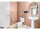 Bathroom with a pedestal sink, toilet, and round mirror at 6533 Waterford Sw St, Atlanta, GA 30331