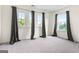 Bright bedroom featuring three windows with elegant curtains and soft carpet at 6533 Waterford Sw St, Atlanta, GA 30331