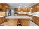 Large kitchen with oak cabinetry, center island with seating, stainless steel refrigerator and tile flooring at 510 Jenna Trl, Mcdonough, GA 30252