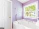 Bright bathroom featuring a white bathtub, a window, and safety grab bars at 2340 Landrum Ct, Lawrenceville, GA 30043