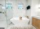 A modern bathroom featuring marble tile, glass shower, soaking tub, and floating double vanity at 3180 Lee Dr, Buford, GA 30518