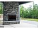 View of the stone fireplace and a green backyard with a wooden fence from the covered back porch at 227 Wet Wood Ct, Fairburn, GA 30213