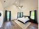 Bright bedroom with vaulted ceiling, wood floor, ceiling fan, and natural light from three windows with blue curtains at 227 Wet Wood Ct, Fairburn, GA 30213