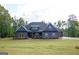 Attractive single-story house featuring a lush green lawn, stone details, and a charming front porch seating area at 227 Wet Wood Ct, Fairburn, GA 30213