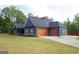 Side view of a home showcasing its spacious two-car garage and beautifully landscaped yard, perfect for Gathering living at 227 Wet Wood Ct, Fairburn, GA 30213