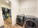 Well-lit laundry room features modern washer and dryer with wood-look tile flooring, plus a large closet with clothing racks at 227 Wet Wood Ct, Fairburn, GA 30213