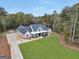 Expansive aerial view of a charming farmhouse with large front yard and a long driveway through a wooded lot at 3911 Peeksville Rd, Locust Grove, GA 30248
