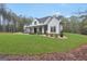 Beautiful modern farmhouse with covered front porch surrounded by landscaped yard, trees, and blue sky at 3911 Peeksville Rd, Locust Grove, GA 30248