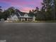 Beautiful exterior view of a modern farmhouse with a covered porch and manicured landscaping at twilight at 3911 Peeksville Rd, Locust Grove, GA 30248