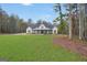 Charming farmhouse exterior view with a covered porch, lush lawn, and surrounding trees at 3911 Peeksville Rd, Locust Grove, GA 30248