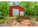 Exterior view of a bright red garage building with roll-up doors, nestled among lush trees at 3313 Henson Ln, Stockbridge, GA 30281