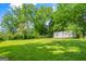 A spacious grassy backyard featuring a metal storage shed, partially shaded by trees, offers utility at 765 Shellnut Dr, Forest Park, GA 30297