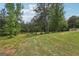 Backyard with expansive green lawn and a few trees and a small shed on a sunny day at 411 Johnson Rd, Locust Grove, GA 30248