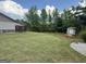 Expansive backyard with lush green grass, mature trees, and a storage shed at 411 Johnson Rd, Locust Grove, GA 30248