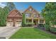 Inviting two-story home with brick and stone accents, a well-manicured lawn, and a three car garage at 2390 Colchester Ct, Cumming, GA 30041