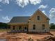 New construction home featuring yellow siding, a covered porch, and a dark roof against a bright blue sky at 242 Old Jackson Rd, Mcdonough, GA 30252