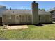 A backyard with a patio, lush lawn, and a charming exterior featuring vinyl siding and a classic chimney at 6372 Stonebridge Creek Ln, Lithonia, GA 30058