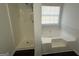 Bathroom featuring a built-in shower and a separate soaking tub under a bright window at 6372 Stonebridge Creek Ln, Lithonia, GA 30058