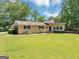 Beautifully maintained ranch home featuring a lush green lawn and mature trees providing shade at 4820 Yeager Rd, Douglasville, GA 30135