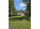 Charming two-story home with a well-manicured lawn, surrounded by lush trees, under a bright blue partly cloudy sky at 175 Forest Lake Dr, Fayetteville, GA 30215