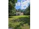 Charming two-story home with a well-manicured lawn, surrounded by lush trees, under a bright blue partly cloudy sky at 175 Forest Lake Dr, Fayetteville, GA 30215