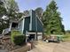 Green two-story home with a garage and lush green trees at 150 Doe Run Ct, Sharpsburg, GA 30277