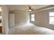 Large carpeted main bedroom with neutral colored walls, a ceiling fan, and a door leading to the main bathroom at 613 Blackburn Ln, Peachtree City, GA 30269