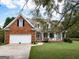 Inviting front exterior with beautiful brickwork, a well-maintained lawn, and mature trees at 557 Arrowhead Cir, Rutledge, GA 30663