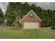A detached brick garage with a white door, nestled among mature trees and greenery at 557 Arrowhead Cir, Rutledge, GA 30663