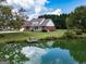 Picturesque pond view with a charming brick home in the background reflecting in the water at 557 Arrowhead Cir, Rutledge, GA 30663