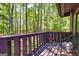 Cozy back porch with seating and wooden railing overlooking a lush green wooded area at 65 Cobblestone Crk, Peachtree City, GA 30269