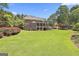 View of the rear of the home featuring a large, well maintained lawn with mature trees at 106 Hidden Springs Ln, Peachtree City, GA 30269
