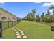Fenced-in backyard featuring a young tree surrounded by a ring of mulch, grass, and stone pathway at 500 Cottonwood Cir, Peachtree City, GA 30269