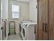 Clean laundry room with washer, dryer, window, tile floors and storage cabinet at 500 Cottonwood Cir, Peachtree City, GA 30269